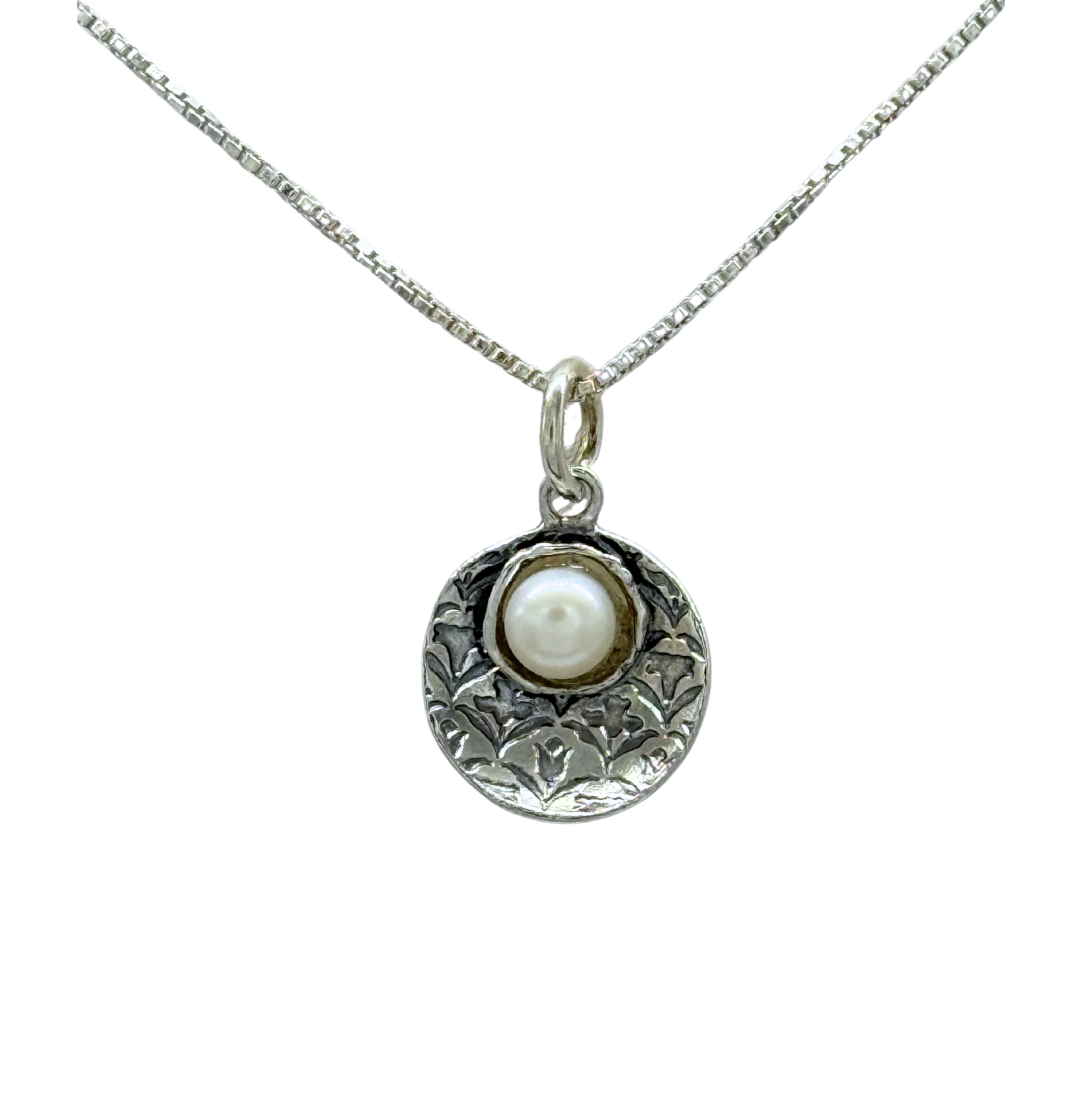 The Fresh Water Pearl in Oxidized Silver Disc Necklace by Mediterranean Artists Co. Sterling Silver features a round, engraved pendant with a central pearl on a textured chain, shown against a white background.