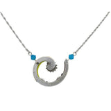 The Spiral Sunburst Multi-Color necklace by Firefly Jewelry is handmade in Guatemala using fair-trade practices. It features a silver spiral pendant with an abstract swirl design, accented by two small blue beads and yellow highlights along the chain.