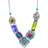 Discover the La Dolce Vita V Multi-Color Necklace by Firefly, a handmade piece crafted with fair-trade practices. This vibrant necklace features a silver chain adorned with multicolored geometric charms, including green elongated shapes and pink, blue, and yellow circular designs.