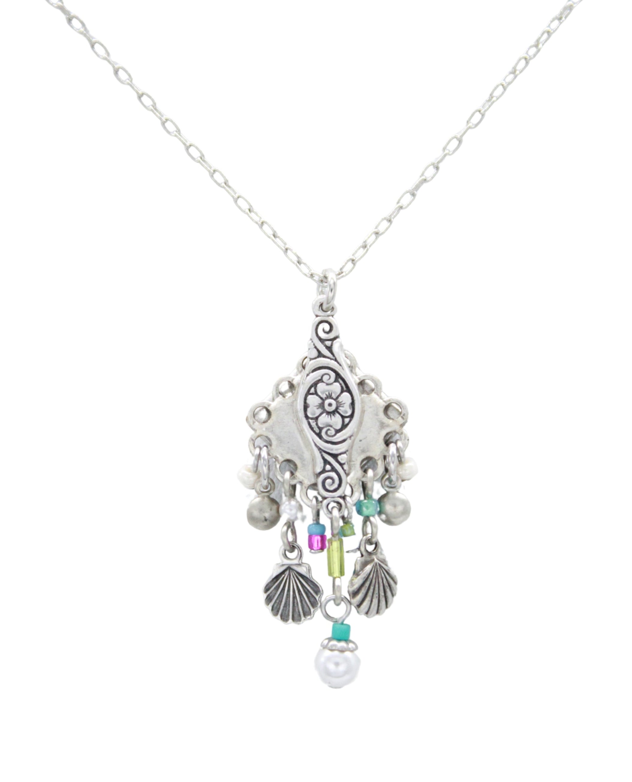 The Beach Pearl Diamond Shell w/Fringe Soft Necklace by Firefly features handmade Guatemalan craftsmanship with a floral pendant, purple, green, and turquoise beads, plus silver shell and sphere charms.