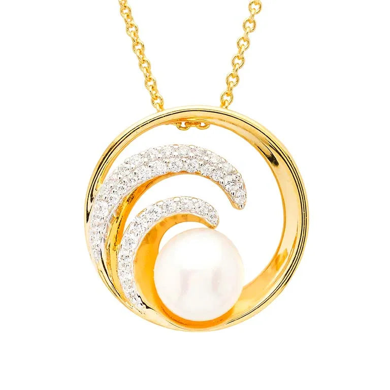 The Shanore Gold Vermeil Ocean Wave with Pearl Necklace features a circular pendant with wave-like curved lines encrusted in cubic zirconia, surrounding a central white pearl. The elegant chain complements its timeless beauty.