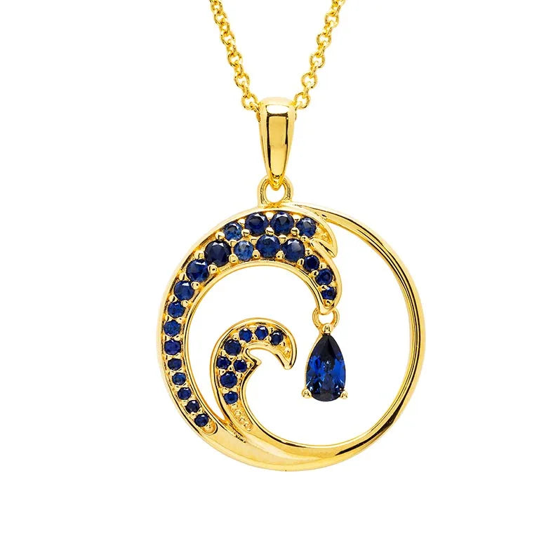 The Shanore Gold Vermeil Blue Sapphire Wave Necklace features a stylized wave pendant with lab-grown sapphires and a teardrop-shaped gem at its center, embodying ocean jewelry. The delicate chain enhances its stunning design.