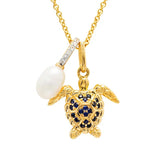 A Shanore Gold Vermeil Blue and White Sapphire Turtle Necklace showcases a detailed turtle with lab-grown sapphires on the shell and a white pearl elegantly hanging from a diamond-studded gold bar.