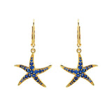 The Shanore Gold Vermeil Blue Sapphire Starfish Earrings- Ocean Jewelry are elegant gold starfish drop earrings with lab-grown sapphires on hooks, presented against a plain white background.