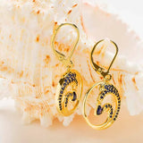Shanores Gold Vermeil Blue Sapphire Wave Earrings from the Ocean Jewelry collection are showcased against a textured seashell backdrop.