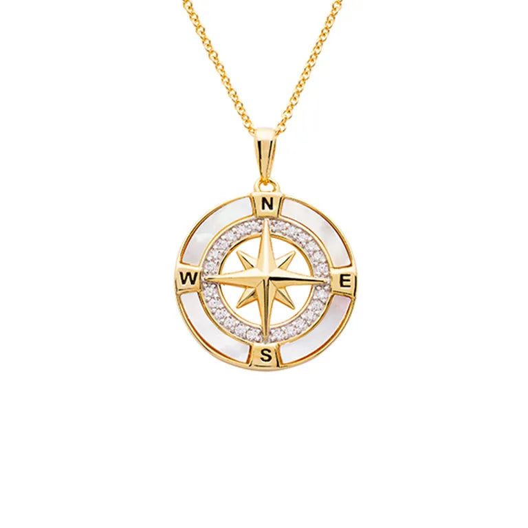 The Gold Vermeil Mother of Pearl Compass Necklace by Shanore features a star at its center, surrounded by N, S, E, and W markers. Small white stones elegantly embellish the circular border against a mother of pearl backdrop.