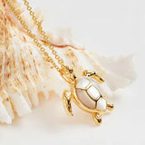 Against a textured, white seashell backdrop, Shanores Gold Vermeil Mother of Pearl Turtle Necklace showcases a gleaming turtle pendant. This piece embodies the elegance of sea turtle jewelry with its lustrous mother-of-pearl-like finish.