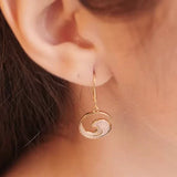 Close-up of an ear adorned with Shanore’s Gold Vermeil Ocean Wave Earrings, showcasing a yin-yang-like circular design with smooth and textured finishes for an elegant touch.