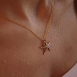 A Shanore Gold Vermeil Starfish Necklace from the Ocean Jewelry collection rests elegantly on a persons slightly wet skin, enhancing its dewy allure.