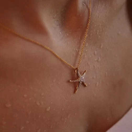 A Shanore Gold Vermeil Starfish Necklace from the Ocean Jewelry collection rests elegantly on a persons slightly wet skin, enhancing its dewy allure.