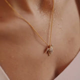 A close-up captures a person wearing the Shanore Gold Vermeil Turtle Necklace- Ocean Jewelry, its cubic zirconia pendant sparkling. Water droplets on their skin create a fresh look, while the softly blurred background highlights the necklace’s intricate 14k gold details.