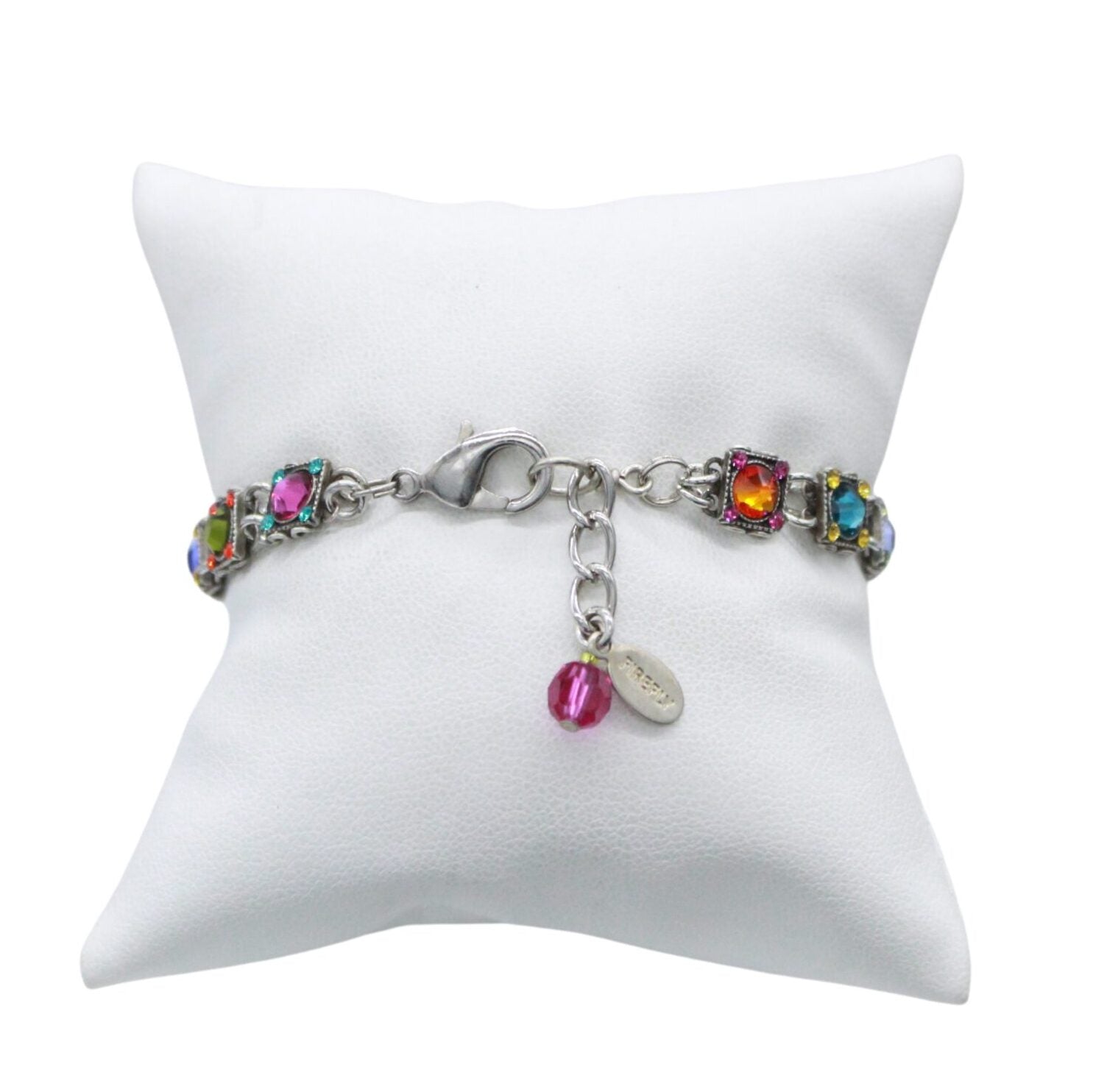 Handmade in Guatemala, Fireflys Thin Rainbow Square Bracelet is fair-trade jewelry showcased on a white cushion. It flaunts colorful square gemstones in silver links, secured with a lobster clasp and an extension chain adorned by a pink bead and metal tag.