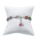 Handmade in Guatemala, Fireflys Thin Rainbow Square Bracelet is fair-trade jewelry showcased on a white cushion. It flaunts colorful square gemstones in silver links, secured with a lobster clasp and an extension chain adorned by a pink bead and metal tag.
