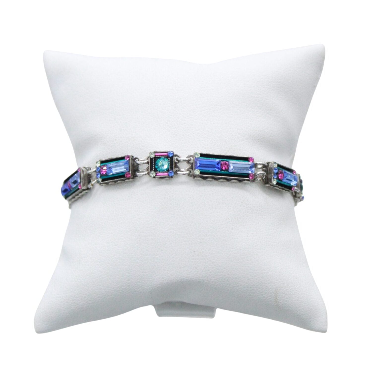 The Architectural Light Turquoise Bracelet by Firefly features rectangular blue gemstones with pink accents, handmade in Guatemala, and is showcased on a white cushioned stand.