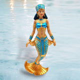 Set against a watery backdrop, the Queen of the Nile Ornament by December Diamonds features a shimmering scaled tail and Egyptian-inspired attire, complete with a blue and gold headdress and matching jewelry—a perfect holiday decor centerpiece embodying mermaid allure.