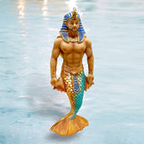 The December Diamonds Pharaoh Nohedidnt Ornament is a striking merman piece featuring Egyptian pharaoh headgear and a muscular torso, with hand-painted golden and turquoise scales on its tail, set against a water background.