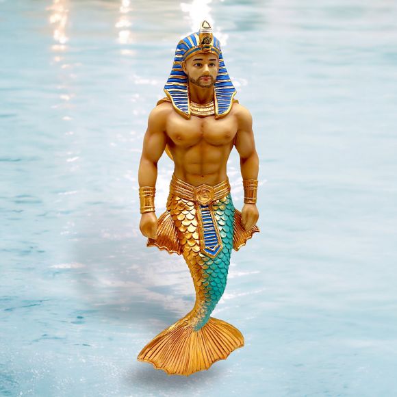 The December Diamonds Pharaoh Nohedidnt Ornament is a striking merman piece featuring Egyptian pharaoh headgear and a muscular torso, with hand-painted golden and turquoise scales on its tail, set against a water background.