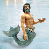 A muscular, gray-haired merman with a beard and necklace holds a shell while standing in clear water. His tail features green scales akin to those on December Diamonds Pearl Collector Ornament often seen in holiday decor.