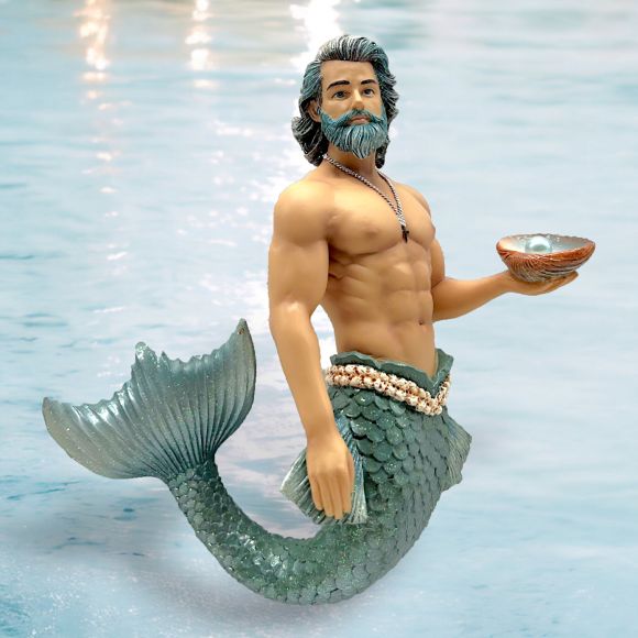 A muscular, gray-haired merman with a beard and necklace holds a shell while standing in clear water. His tail features green scales akin to those on December Diamonds Pearl Collector Ornament often seen in holiday decor.