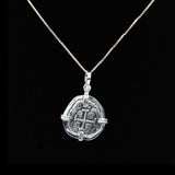 Set against a black backdrop, The Treasure Shoppe Inc.s sterling silver Atocha 302 Coin pendant captures the historical essence of Atocha shipwreck coins. Its worn engravings feature a central cross with indistinct details, elegantly hanging from the thin silver chain.