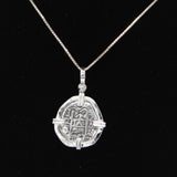 The Treasure Shoppe Inc.s Atocha 302 Coin Pendant resembles a mysterious Sterling silver Atocha coin with symbolic inscriptions set in a cross-shaped frame. Hanging elegantly against a black background, it whispers tales of historical significance.