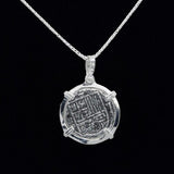 This exquisite Bogota Coin pendant by The Treasure Shoppe Inc. is crafted in sterling silver with intricate engravings, framed in a simple bezel, set against a black background, and makes for an elegant addition to any chain.