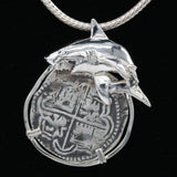 The Treasure Shoppe Inc.s 8 Reale Shark Coin Pendant, crafted in sterling silver, features a shark motif over a round Atocha shipwreck coin with cross-like symbols. The intricate metalwork stands out against its black background and comes with a braided chain for wearing.