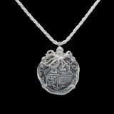 The Treasure Shoppe Inc.s Large Octopus Coin - Atocha Shipwreck pendant features an intricately designed medallion styled like an old coin, topped with a small octopus figure and encased in a sterling silver bezel, hanging from a braided silver chain against a black background.