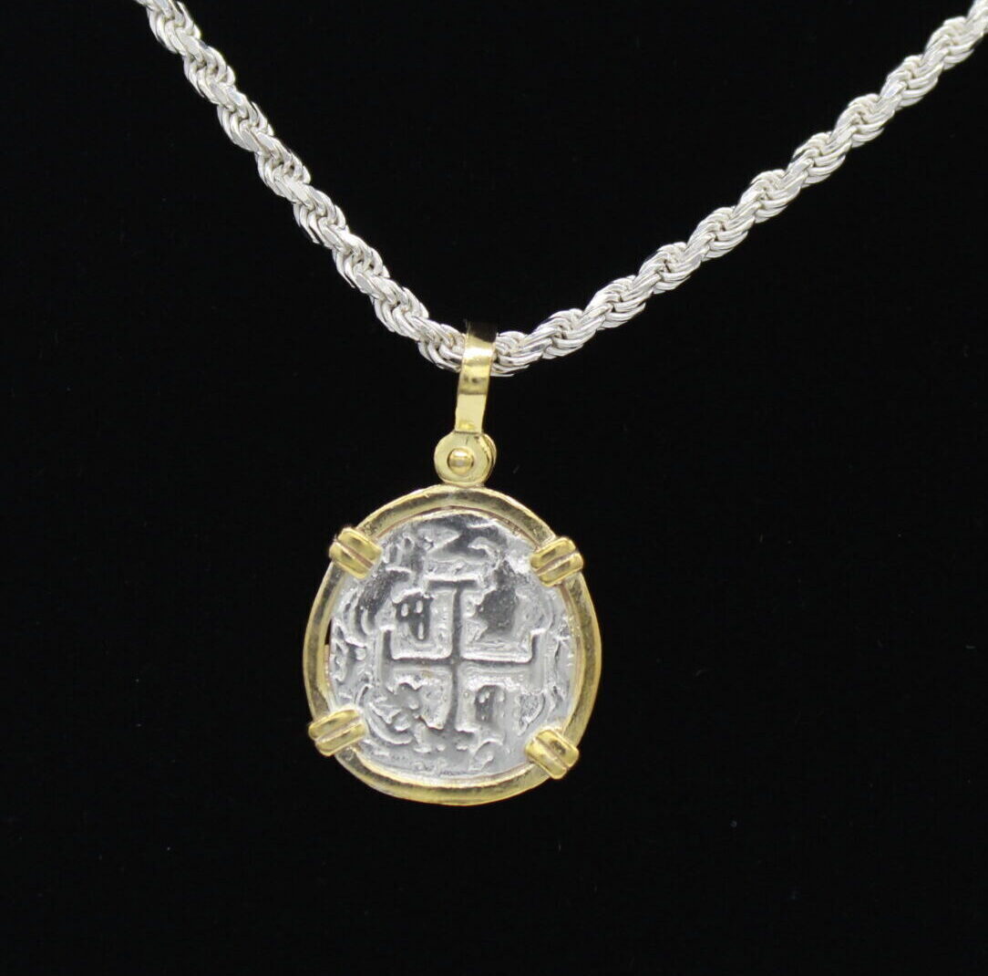 The Treasure Shoppe Inc.s Gold Plated Reale/Oblong Coin-Atocha Shipwreck Pendant features a historic Atocha coin with a cross and markings, elegantly hanging from a twisted sterling silver chain against a black background, exuding timeless charm.
