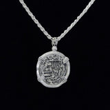 The Treasure Shoppe Inc.s 502 Coin pendant, reminiscent of Atocha shipwreck coins, features intricate ancient-style engravings on sterling silver. The design is highlighted by a twisted chain and black background to showcase its historic charm.