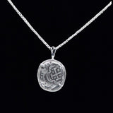 The Treasure Shoppe Inc.s 1 Reale Coin- Atocha Shipwreck Coins pendant showcases intricate oval details on a delicate sterling silver chain, set against a black backdrop, exuding a historic charm akin to cherished Atocha coins.