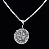 The Treasure Shoppe Inc. presents the 8 Reale Triple Prong Coin Pendant, inspired by Atocha shipwreck coins. This pendant showcases intricate patterns and historic charm, reminiscent of Atocha coins, beautifully dangles from a textured chain against a black background (chain not included).