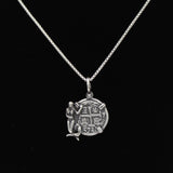 The Treasure Shoppe Inc.s Medium Mermaid Coin features an engraved round sterling silver bezel pendant with symbols and a detailed figure on the left, reminiscent of shipwreck coins. The pendant is displayed against a black background without a chain.