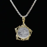 The Treasure Shoppe Inc.s Gold Plated Dolphin Frame Coin, inspired by Atocha shipwreck treasures, features a rustic silver coin pendant set in an ornate gold plated design, hanging on a thick silver rope with a solid black backdrop.