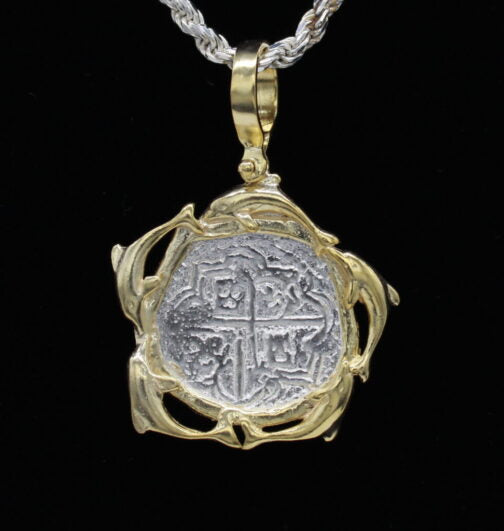 The Treasure Shoppe Inc.s Gold Plated Dolphin Frame Coin—Atocha Shipwreck Coins (Pendant Only) features a historic coin framed with elegant vine-like gold swirls, reflecting maritime history. Suspend from your favorite chain to capture its allure against any backdrop.
