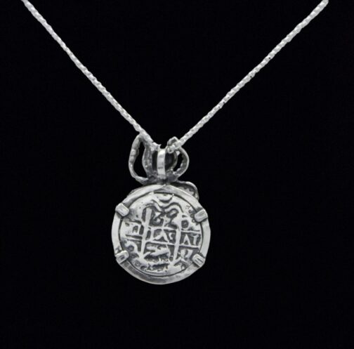 The Treasure Shoppe Inc.s Medium Antique Octopus Coin pendant, inspired by Atocha Shipwreck Coins, features an engraved design on sterling silver, displayed elegantly on a delicate chain against a black background.