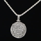 The Treasure Shoppe Inc.s 8 Reale 2 Prong Coin-Atocha Shipwreck Pendant boasts intricate designs in a simple metal frame. It dangles from a twisted sterling silver bezel chain against a black background, reminiscent of Atocha Coins.