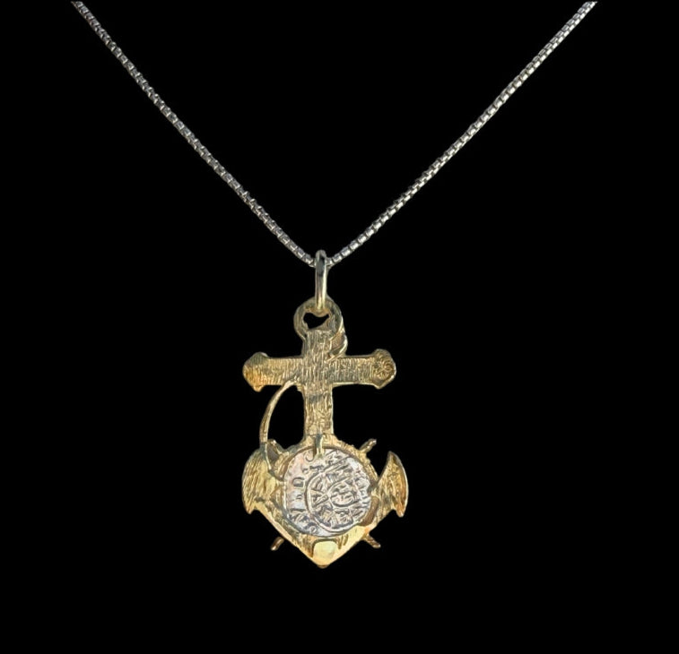 The Treasure Shoppe Inc.s Gold Plated Anchor Coin- Atocha Shipwreck Coins pendant features a cross and anchor design with an intricate circular element, reminiscent of Atocha coins, elegantly showcased on a delicate chain against a black background.
