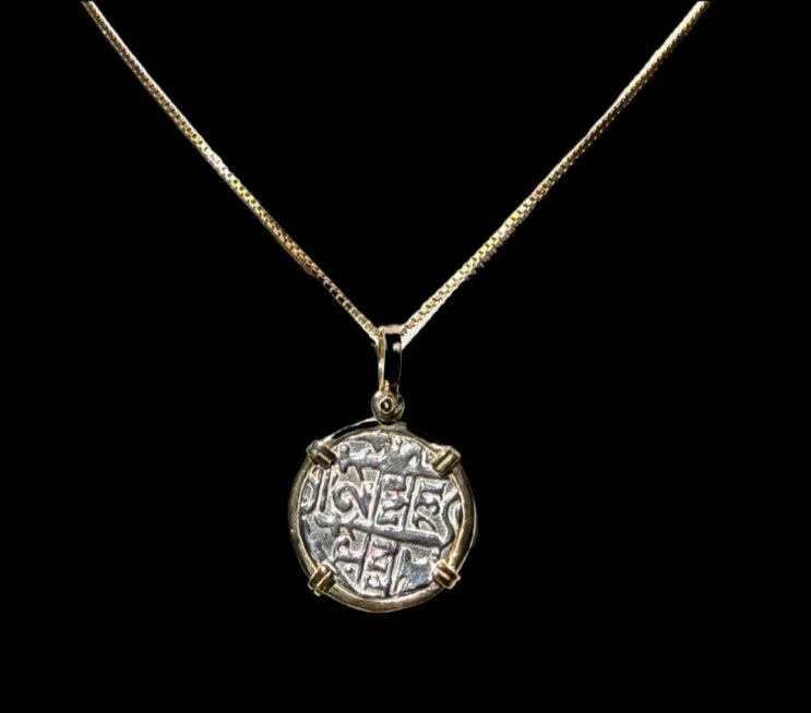 A Gold Plated Round Reale Coin-Atocha Shipwreck Coin pendant from The Treasure Shoppe Inc., with an ancient design and intricate patterns, is elegantly showcased against a solid black background.