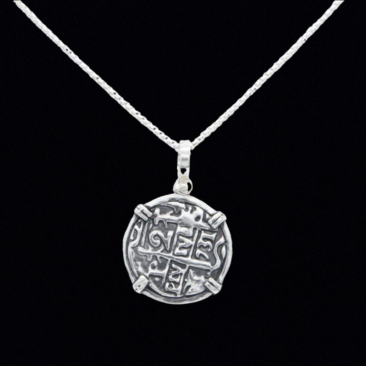 The Treasure Shoppe Inc.s Silver Round Reale Coin- Atocha Shipwreck Coins pendant features a round coin-like medallion with an abstract design, set in a sterling silver bezel and displayed against a black background, minus the chain.