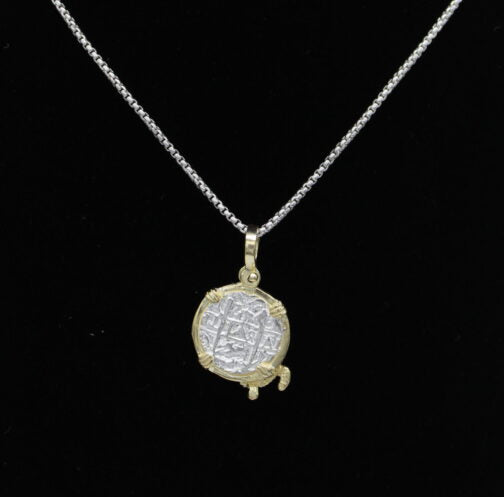 A silver chain necklace features The Treasure Shoppe Inc.s Gold Plated Small Turtle Coin- Atocha Shipwreck Pendant, capturing historic charm with its ornate gold-tone frame against a black background.