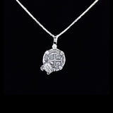 The Silver Small Turtle Coin by The Treasure Shoppe Inc. features a turtle on a textured coin surface inspired by Atocha shipwreck coins, framed in a sterling silver bezel against a striking black background.