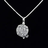 The Treasure Shoppe Inc.s Silver Small Turtle Coin from the Atocha Shipwreck is elegantly mounted in a sterling silver bezel, featuring engraved symbols and resting against a black background.