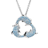 The Swarovski Crystals Three Dolphins Necklace by Shanore, an exquisite Ocean Jewelry piece, features a sterling silver pendant with intertwined dolphins adorned with light blue and clear Swarovski crystals. The elegant design hangs gracefully from a delicate chain.