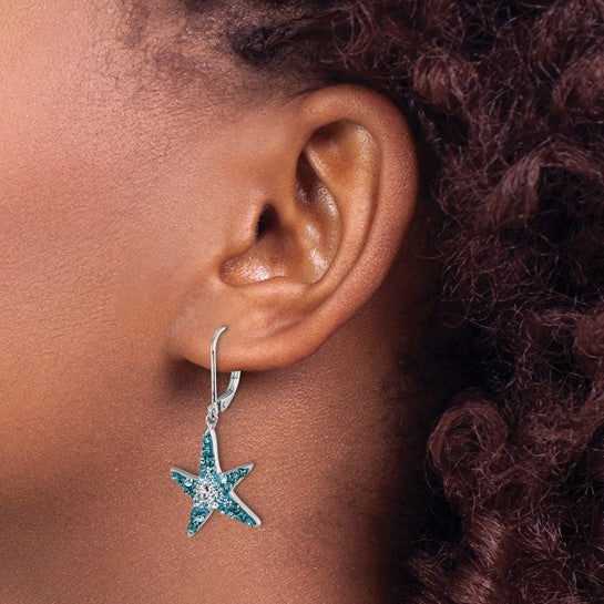 Close-up of a persons ear with curly hair wearing Presco/Quality Gold’s Crystal Blue Starfish Earrings, crafted in sterling silver and accented with blue and clear Swarovski crystals.