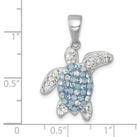 The Presco/Quality Gold Crystal Blue/Clear Turtle Pendant features clear and light blue gemstones on its sterling silver shell, displayed against an inch grid for scale—a distinctive crystal jewelry piece.