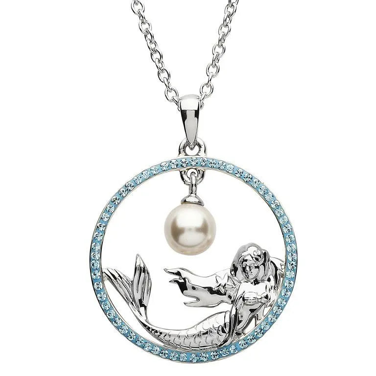 The Shanore Swarovski Crystals Circle Mermaid with Pearl Necklace features a mesmerizing mermaid pendant within a gem-studded circular frame. The enchanting mermaid holds a central pearl, completing this elegant piece of ocean jewelry.