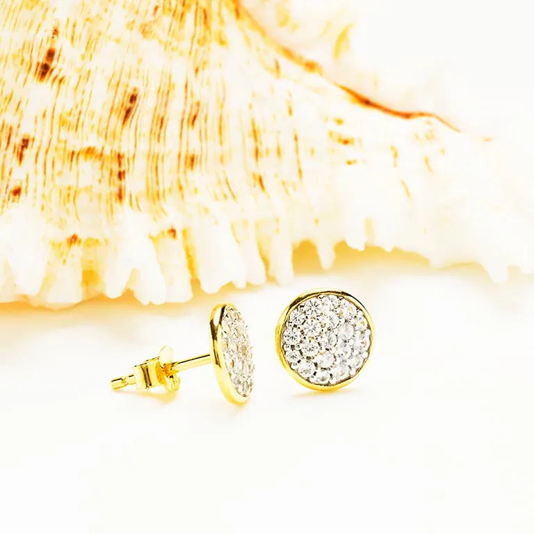 Shanores Gold Vermeil White CZ Stud Earrings from the Ocean Jewelry line glimmer elegantly against a textured seashell backdrop.