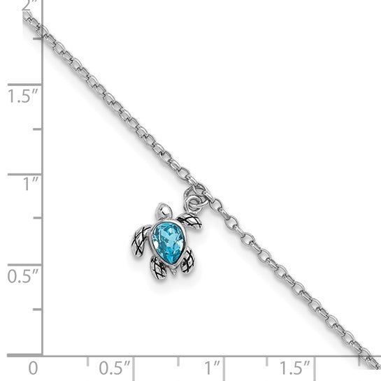 The Presco/Quality Gold Crystal Turtle Dangle Aqua Cry Anklet features a small turtle charm with a teardrop-shaped blue gemstone, shown on an inch-marked background for size reference.