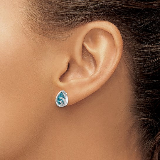 Close-up of a womans ear wearing Crystal Aqua Wave Post Earrings by Presco/Quality Gold—small sterling silver teardrop studs with a blue background and white wave design.